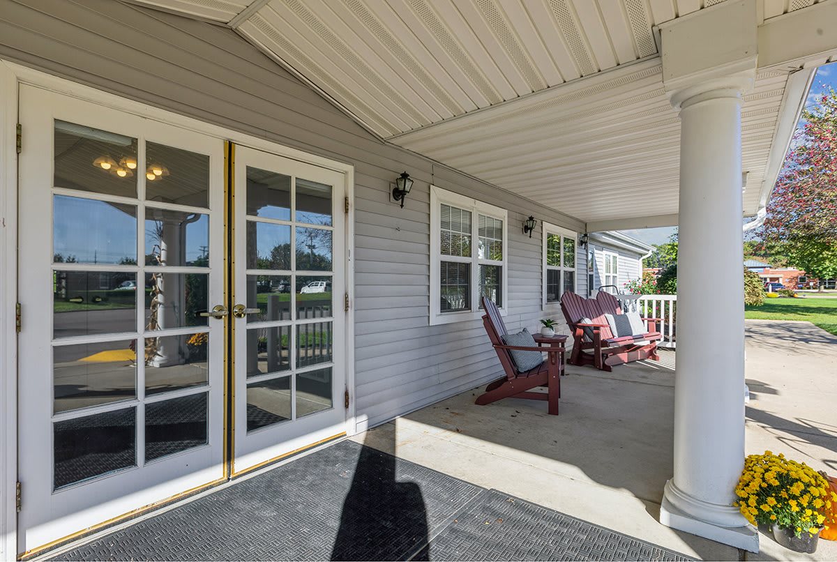 A cozy porch with outdoor seating and windows on a house exterior.