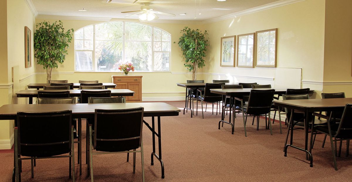 A well-lit classroom with tables and chairs arranged for a meeting or class.