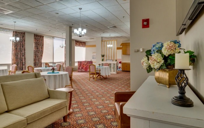 A cozy lobby interior with seating areas, tables, and elegant chandeliers.