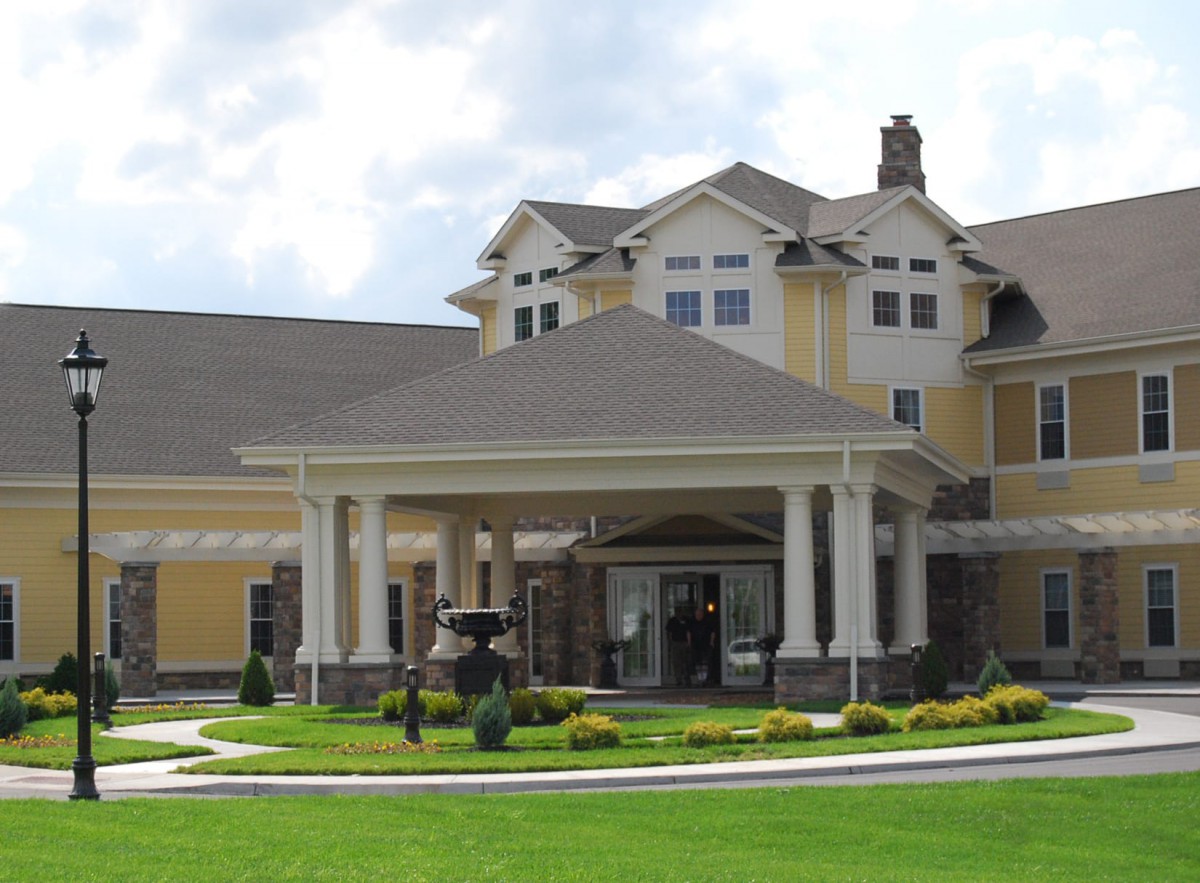 A large, elegant residential building with a well-maintained landscape and circular driveway.