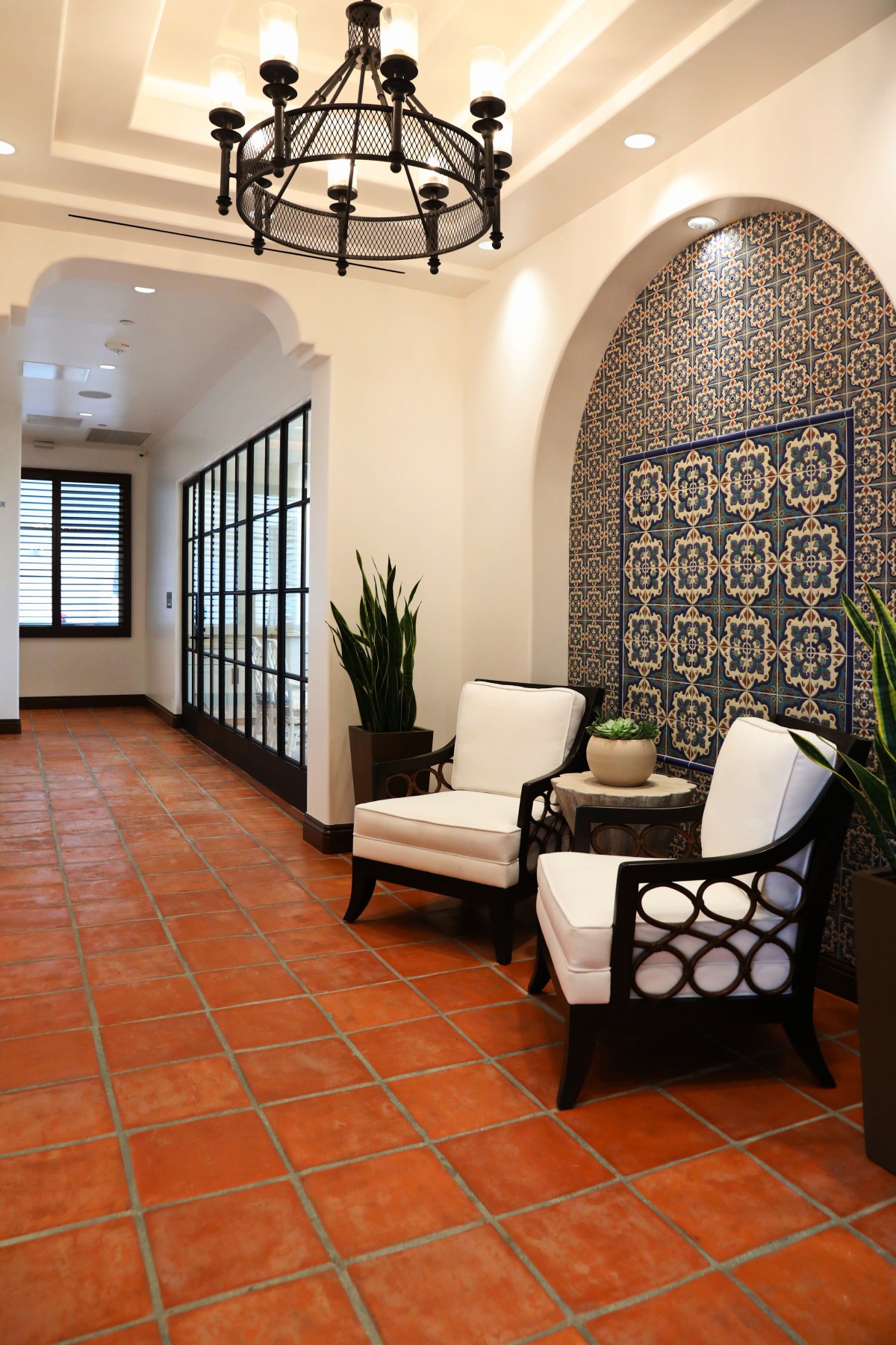 A stylish lobby seating area featuring armchairs, decorative tiles, and warm lighting.