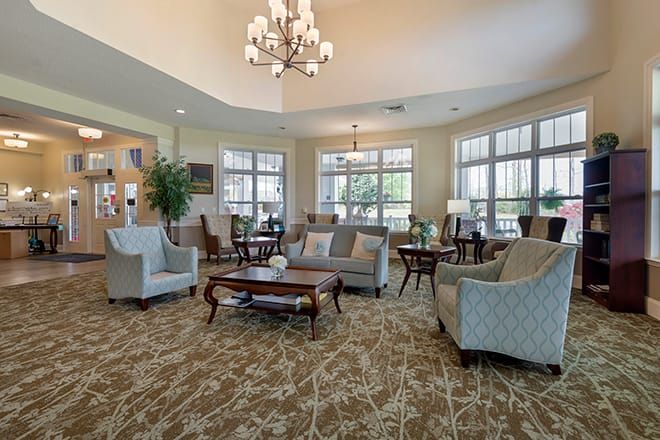 A spacious and elegantly furnished living room featuring a chandelier, comfortable sofas, and large windows.