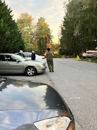 A quiet street scene with parked cars and a few individuals conversing.