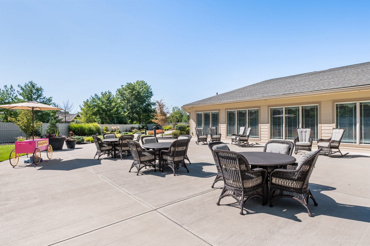 A sunny outdoor patio area with tables and chairs near a building.