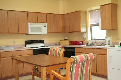 A cozy kitchen featuring wooden cabinetry, a dining table with striped chairs, and modern appliances.