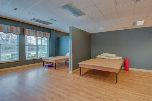 A clean and minimalistic hospital room featuring two unmade beds and ample natural light.