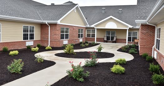 A well-maintained garden with a curved walkway leading to a brick building.