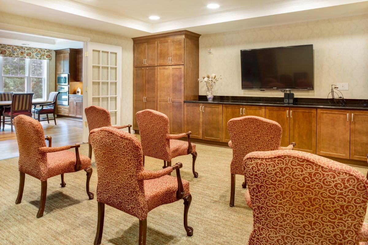 A well-furnished conference room with multiple chairs facing a large television.