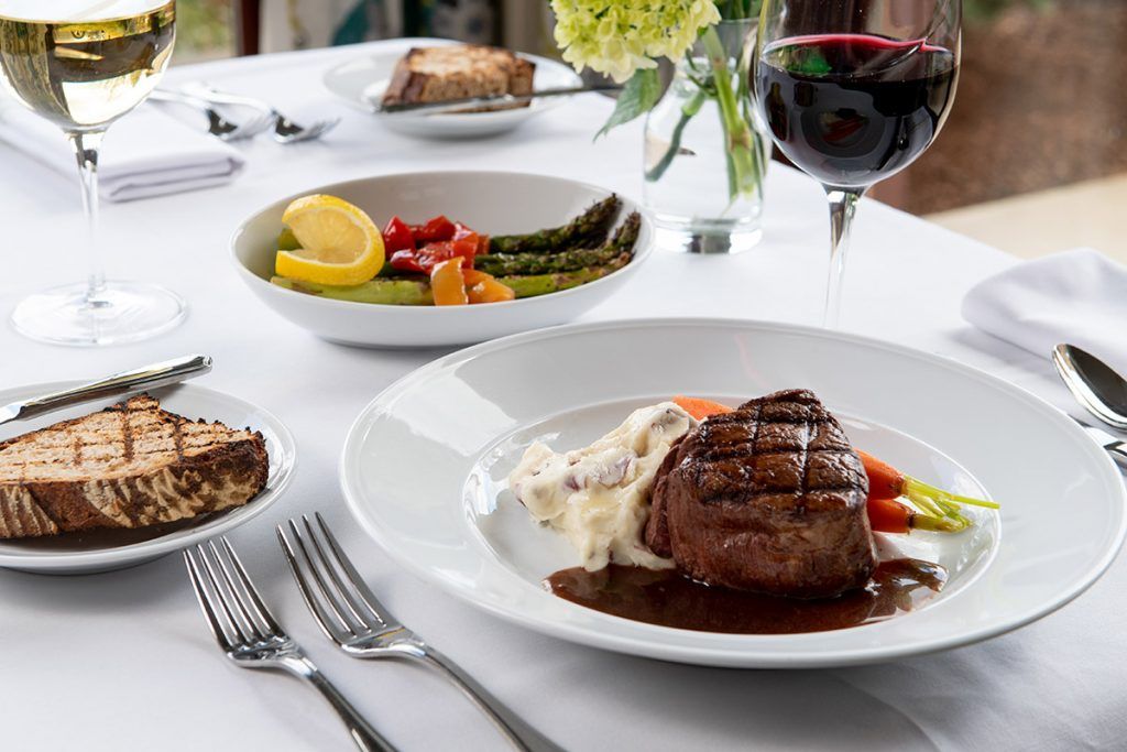 A gourmet steak dinner served with asparagus and accompanied by a glass of red wine.