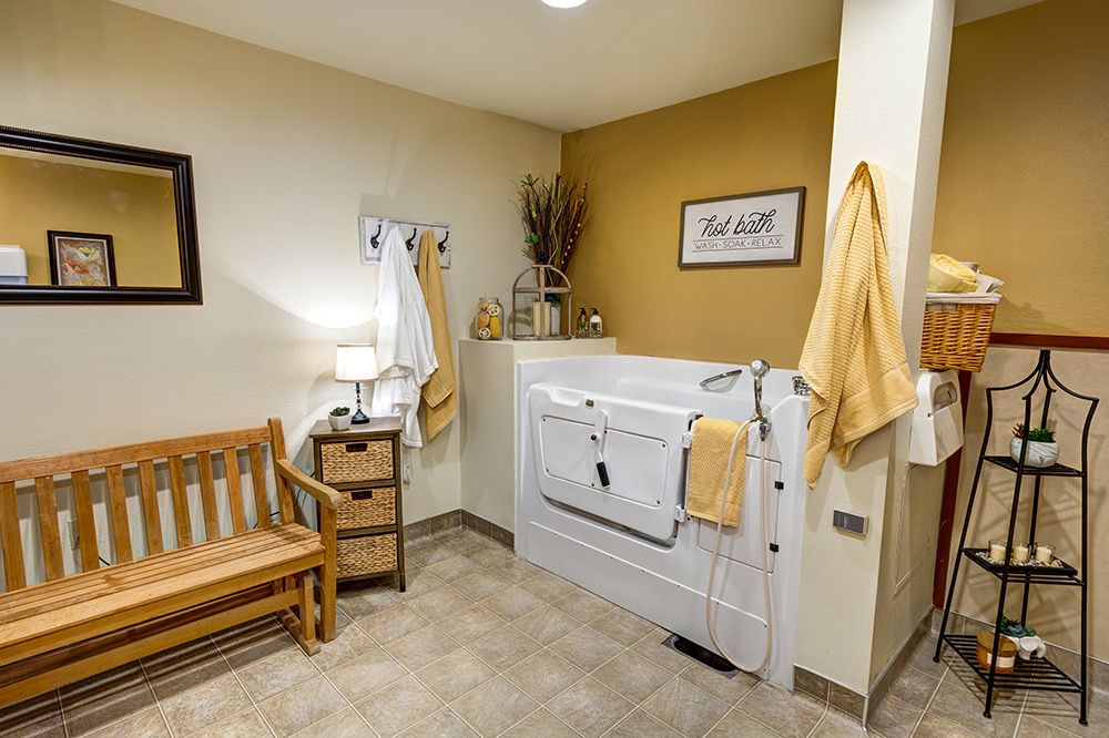 A cozy and accessible bathroom featuring a walk-in tub, wooden bench, and warm decor.