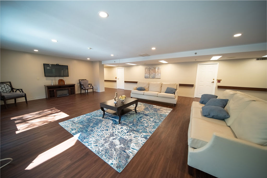 A spacious living room with modern furnishings, featuring a large rug, comfortable sofas, and a central coffee table.
