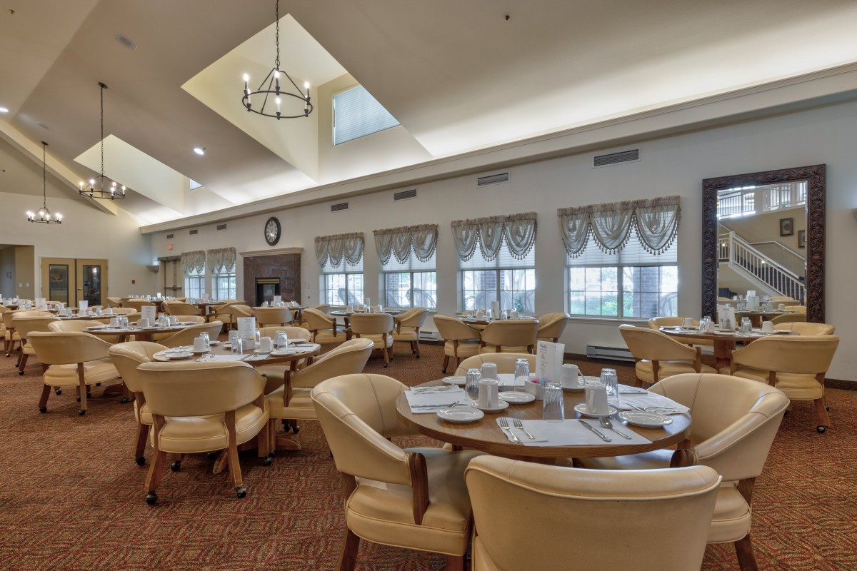 A well-lit dining room with neatly set tables and comfortable chairs.