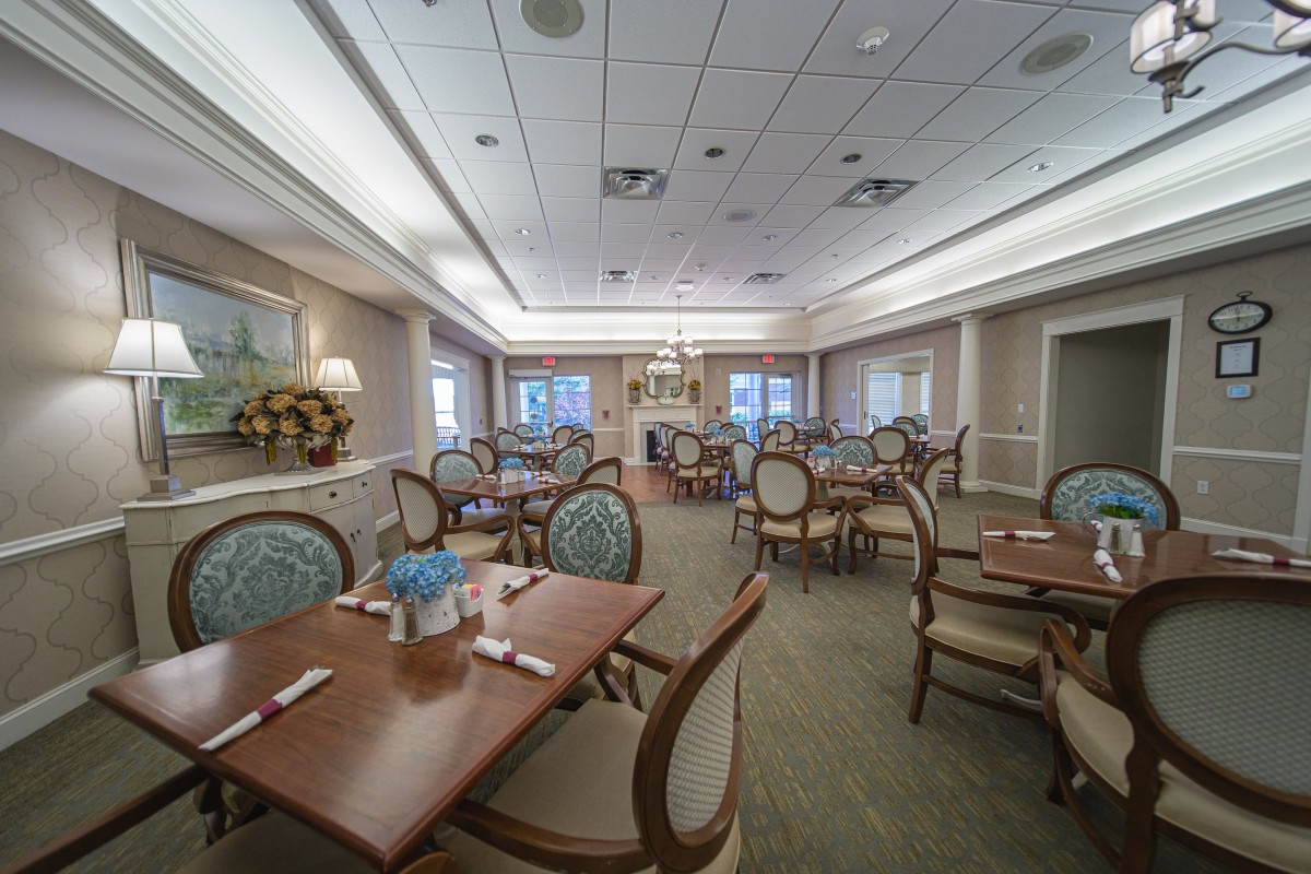 An elegant dining room with neatly arranged tables and chairs, featuring classic decor and ambient lighting.