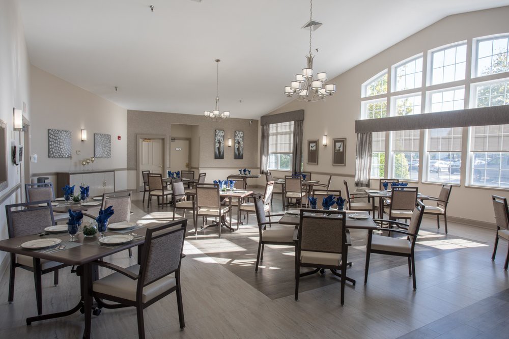 An empty dining room with neatly arranged tables and chairs, well-lit by natural light through large windows.