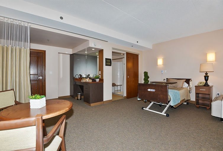 A clean and modern hospital room with a bed and seating area.