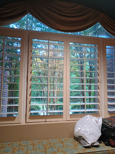 A view from inside looking out through wooden blinds, showcasing a serene natural landscape.