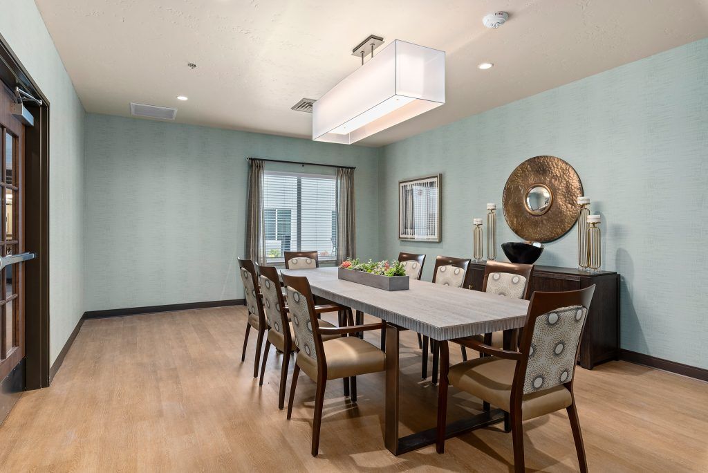 A stylish dining room with a long table, multiple chairs, and elegant lighting.