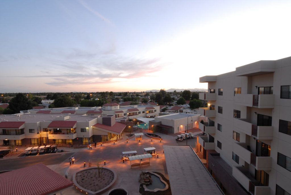 A cityscape at sunset, with buildings illuminated by street lights.