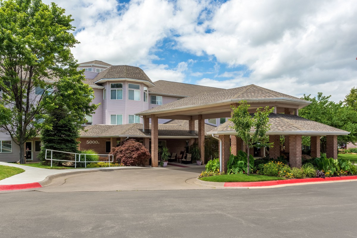 Exterior view of a building with a welcoming entrance and landscaped surroundings under a cloudy sky.