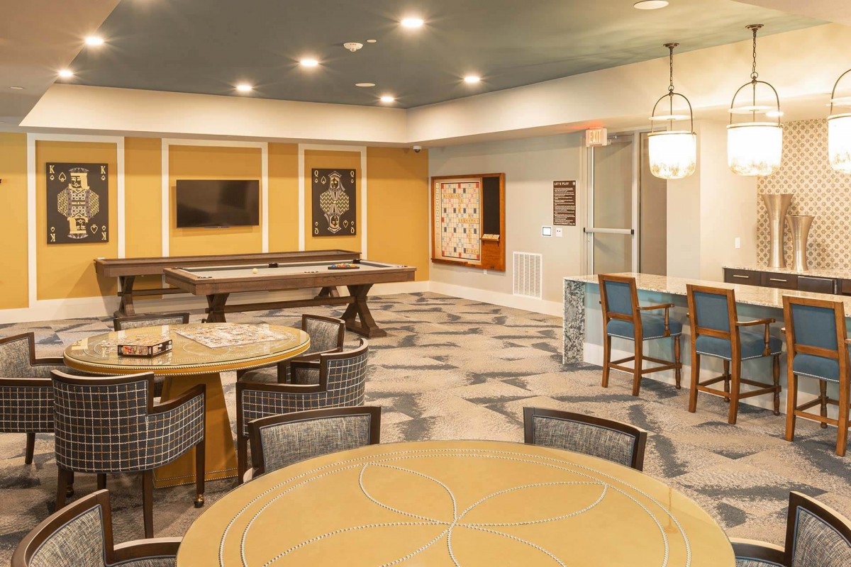 A modern lounge area with tables and chairs, decorated with stylish lighting and artwork.