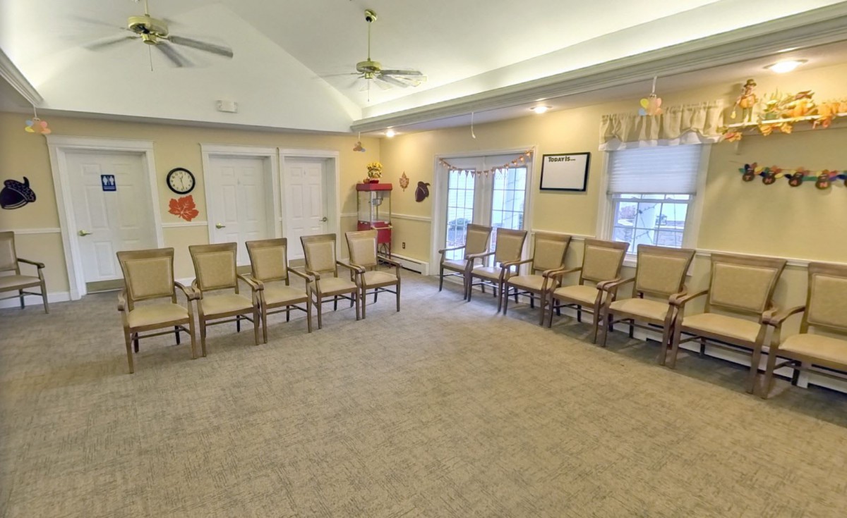 An empty waiting room with several chairs arranged around the walls.