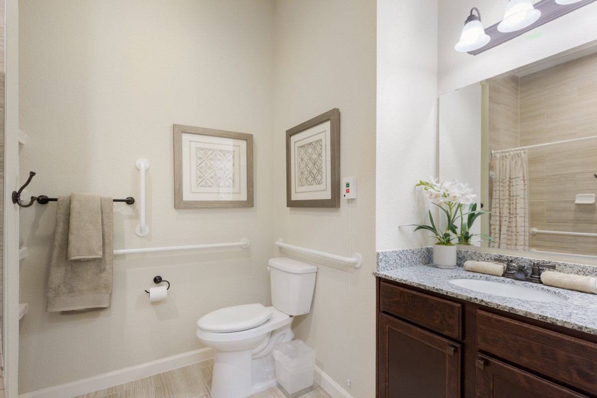 A modern bathroom featuring a toilet, sink with mirror, and decorative wall art.