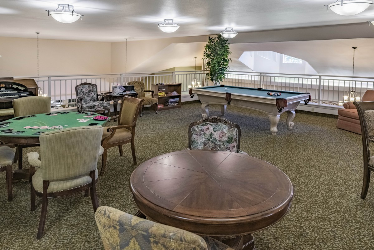 A cozy game room featuring a pool table, poker table, and various seating options.