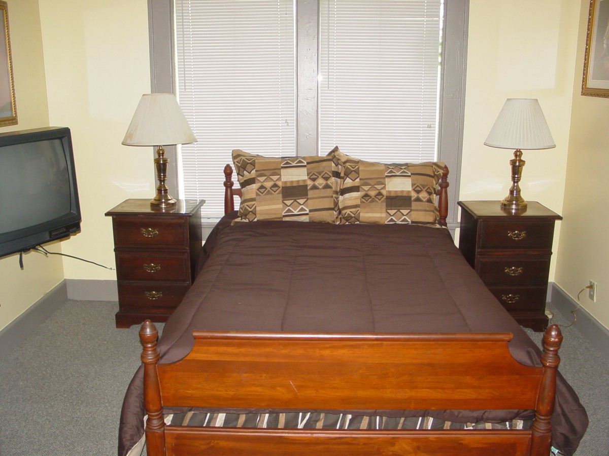 A neatly arranged bedroom with a wooden bed, two nightstands, and two lamps.