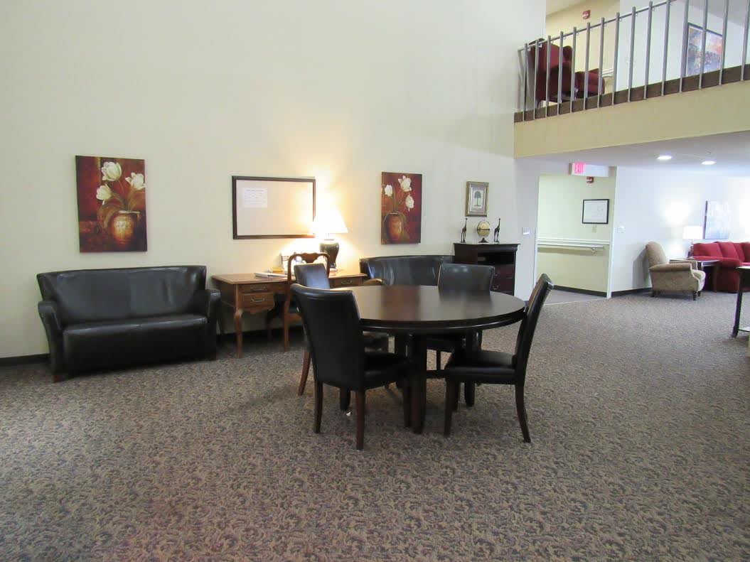A cozy lobby area featuring a round table with chairs, a sofa, and decorative artwork on the walls.