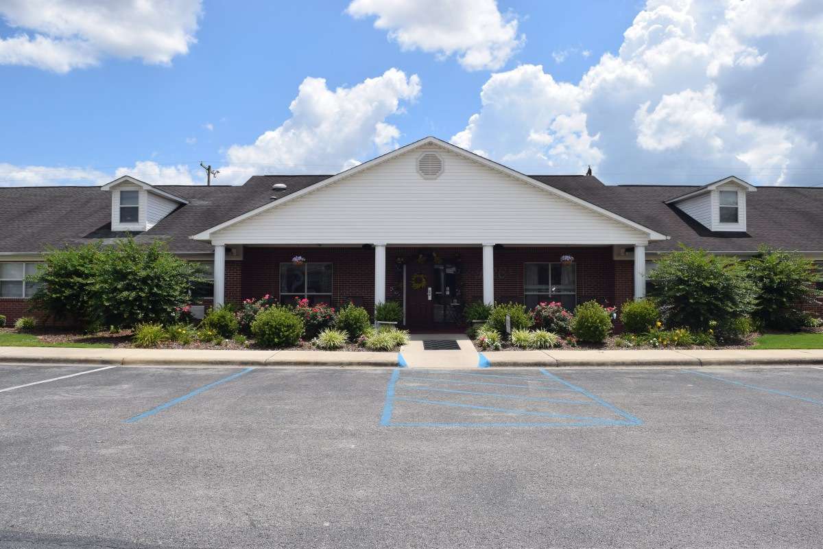 A single-story building with a gabled roof and landscaped entrance under a partly cloudy sky.