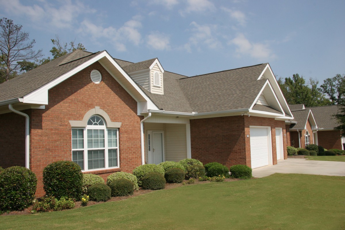 A suburban brick house with a well-maintained lawn and a two-car garage.