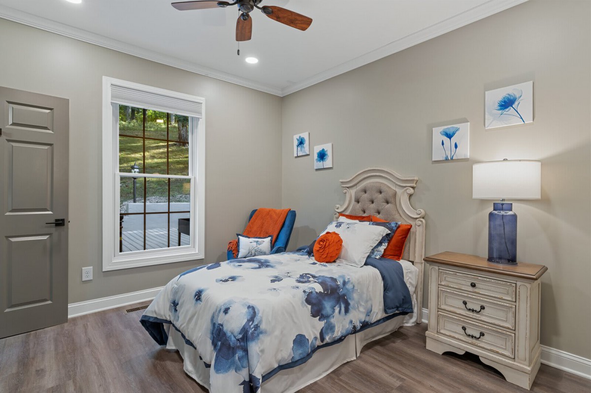 A cozy bedroom with elegant decor featuring a bed with floral bedding, a nightstand, and wall art.