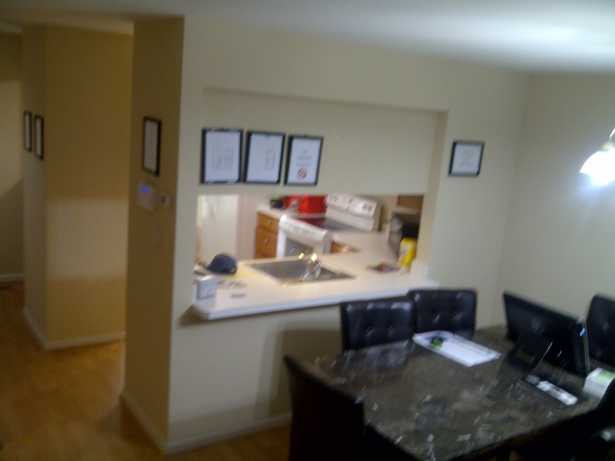 An open kitchen view from the dining area with a countertop and chairs.