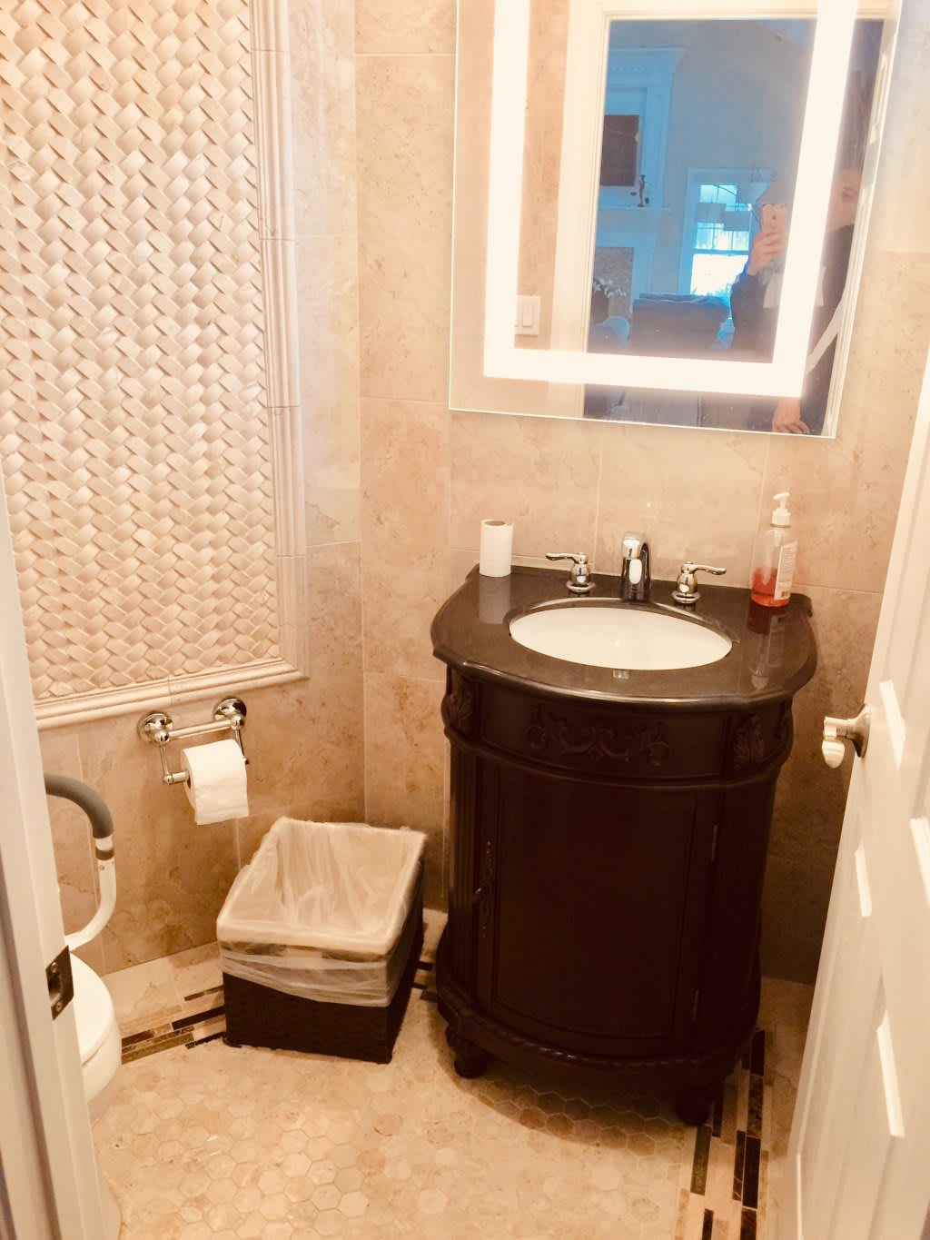A compact bathroom with a tiled wall, featuring a sink, toilet, and mirror.