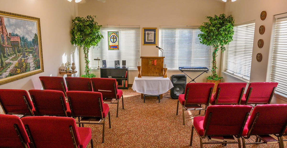 An intimate church interior featuring a podium, red chairs, and audio equipment.