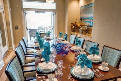 An elegantly arranged dining table set for a formal meal, featuring blue napkins and intricate decor.