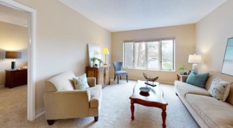 A cozy living room featuring comfortable sofas, a classic wooden coffee table, and large windows letting in natural light.
