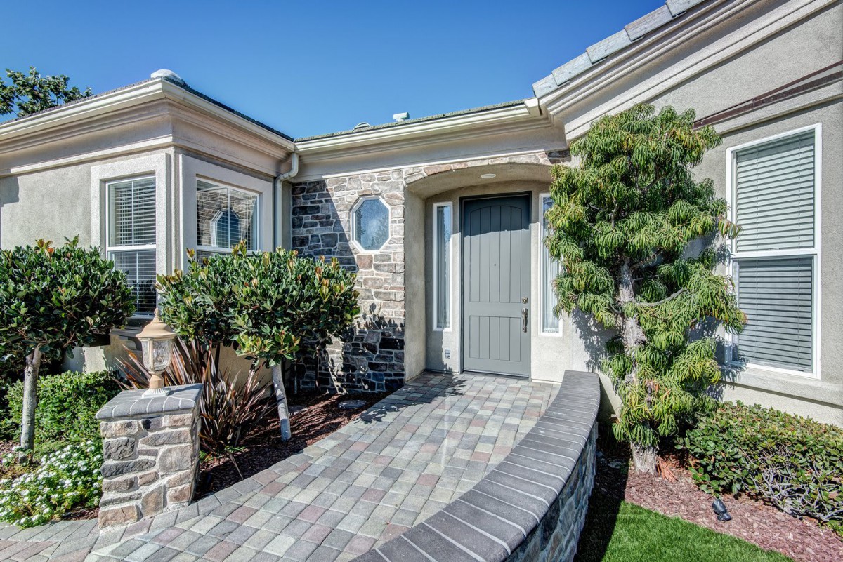 Charming house entrance with brick pathway and lush landscaping.