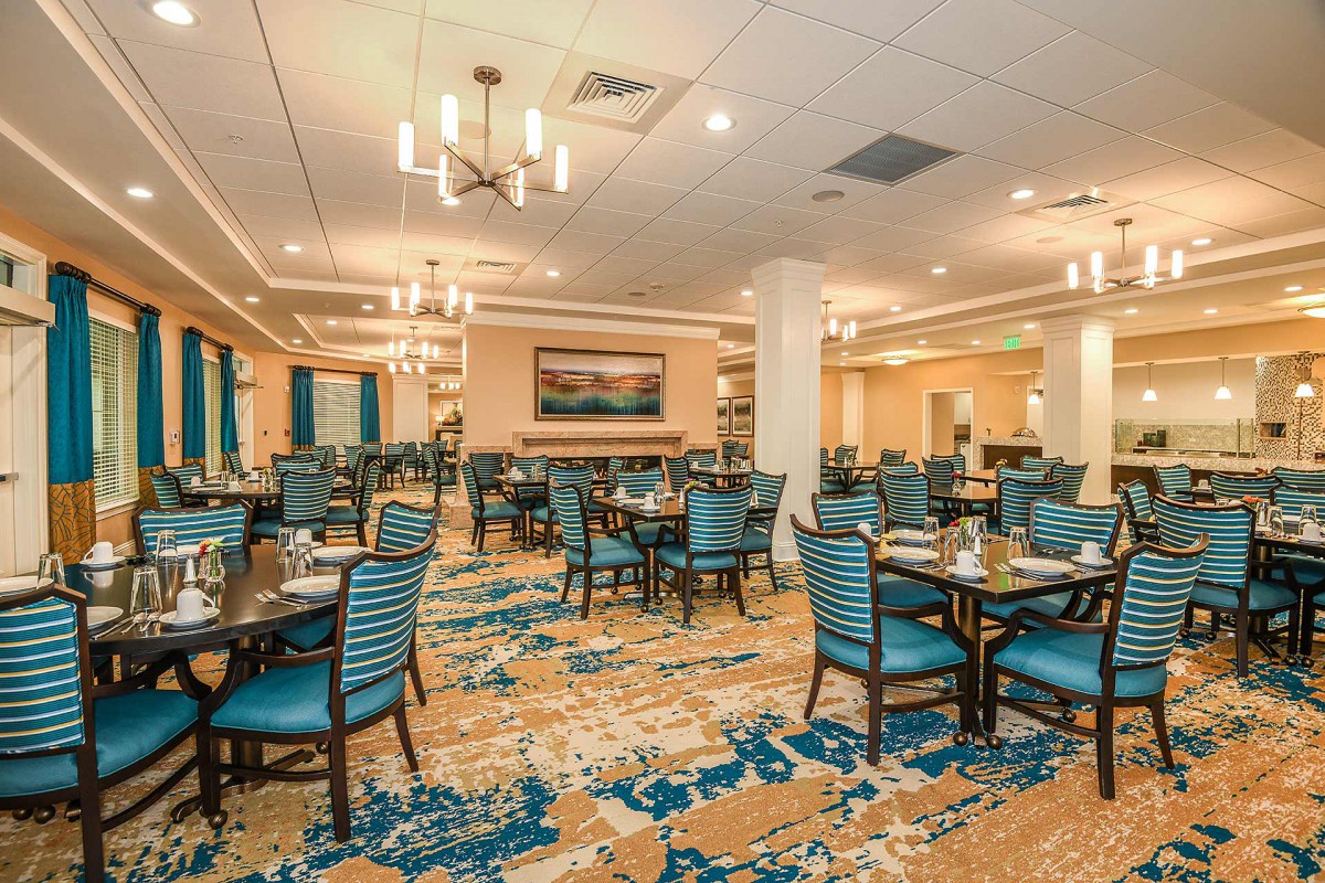 A spacious and elegantly decorated dining area with tables set for service, featuring modern lighting and a colorful carpet.