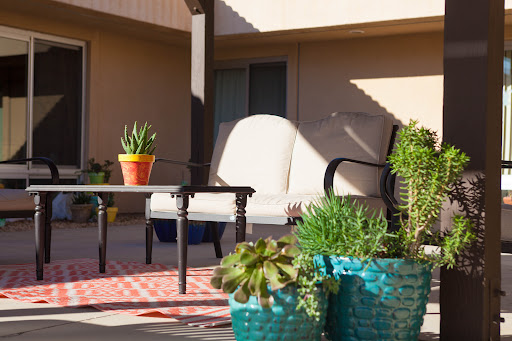 A cozy outdoor patio setup with comfortable seating and vibrant potted plants.