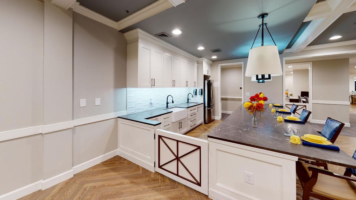 A modern kitchen with sleek countertops, pendant lighting, and light wood flooring.