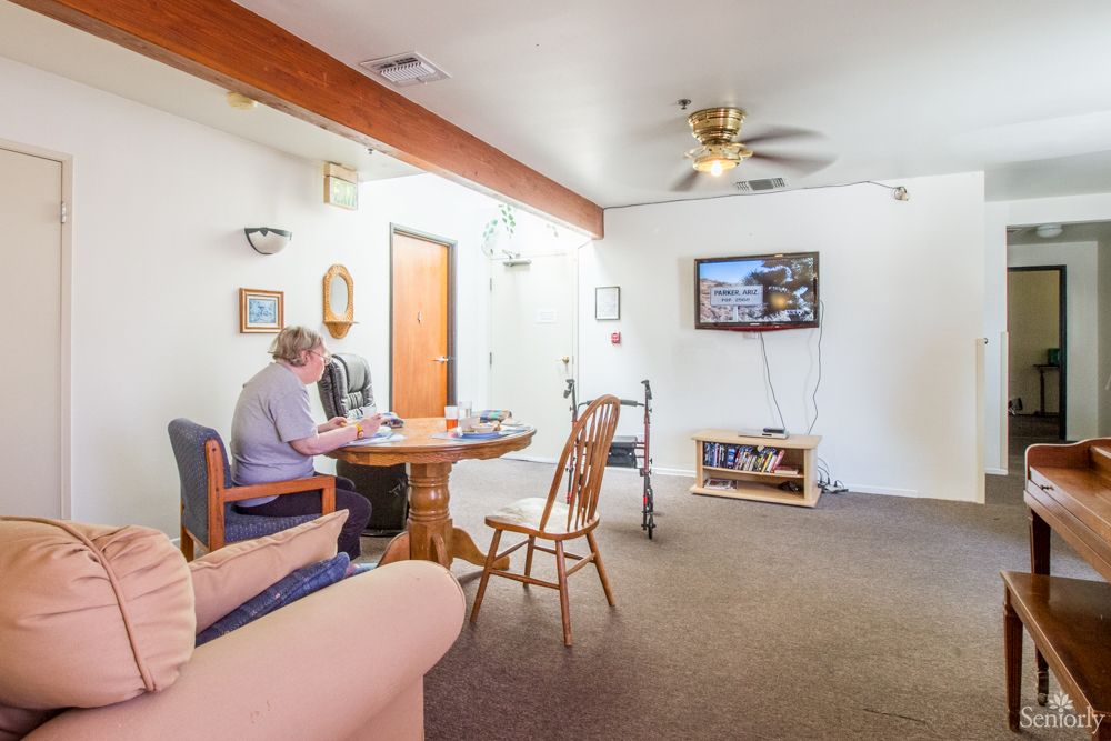 A spacious living room with a dining area, featuring a television and ceiling fan.
