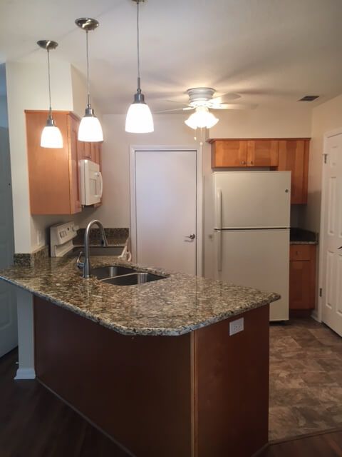 A modern kitchen featuring a granite countertop and pendant lighting.