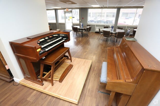 A room featuring a wooden organ and piano, surrounded by a comfortable seating area on a wooden floor.