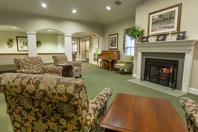 A cozy living room featuring comfortable seating, a fireplace, and a piano.