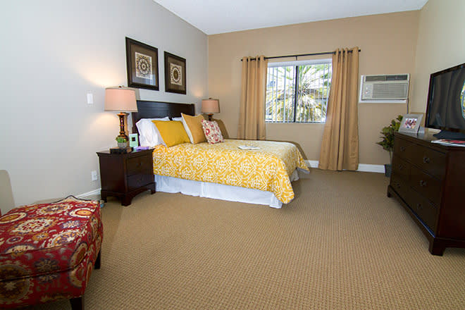 A cozy bedroom with a neatly made bed, soft lighting from table lamps, and a view out the window.