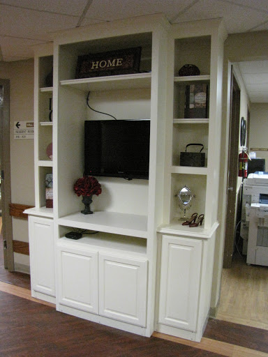 A modern white entertainment center featuring shelves for decor and a TV.