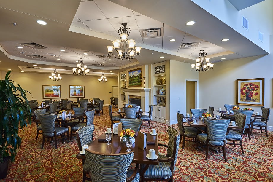 An elegantly decorated dining room with multiple tables and chandeliers.