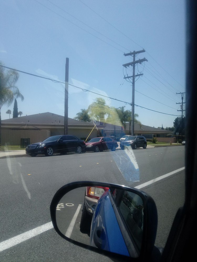 A view of cars parked along the street with power lines overhead.