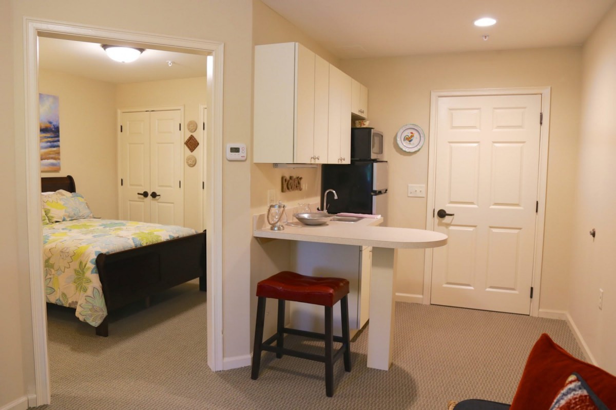 A cozy kitchenette area adjacent to a bedroom in a small apartment.